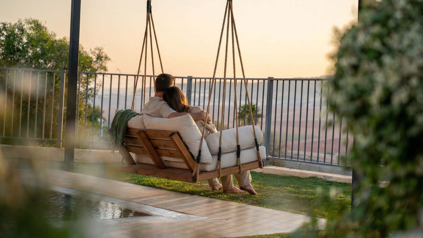 זוג נרגע על הנדנדה הזוגית מול עמק המעיינות בשעת זריחה